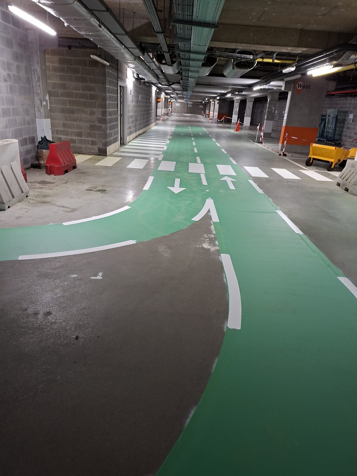 Groen epoxy fietspad met routebelijning in een ondergrondse parking